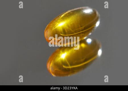 Gros plan d'une capsule de gel souple unique avec réflexion sur la surface brillante Banque D'Images