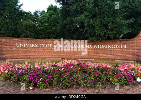 Wilmington, NC – 2 octobre 2025 : un panneau en briques entouré de fleurs accueille les visiteurs sur le campus de l'Université de Caroline du Nord Banque D'Images