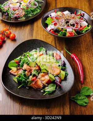 Saladiers frais et colorés avec légumes et saumon sur une table en bois Banque D'Images