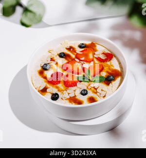 Délicieux bol de flocons d'avoine garni de fruits frais et de sirop sur une table Banque D'Images
