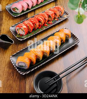 Plateaux de sushi avec des rouleaux assortis affichés sur une table en bois Banque D'Images
