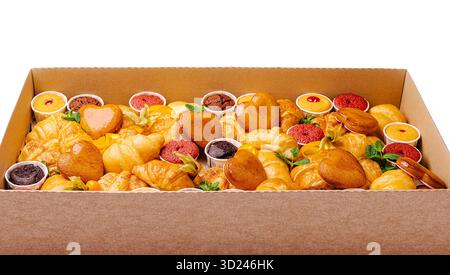 Une variété de pâtisseries, y compris des croissants et des mini-friandises sucrées, sont magnifiquement disposées dans une grande boîte. L'assortiment comprend des desserts colorés Banque D'Images