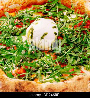 Pizza fraîchement préparée garnie de roquette et de fromage crémeux dans un restaurant rustique Banque D'Images