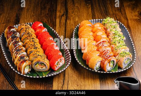 Plateaux de sushi avec divers rouleaux et sashimi sur une table en bois Banque D'Images