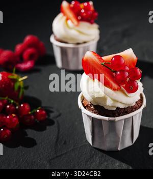 Délicieux cupcakes au chocolat garnis de baies fraîches et de crème Banque D'Images