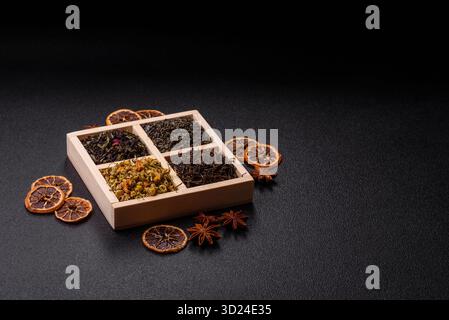 Une boîte en bois avec plusieurs types de thé séché, vert, noir, fruit, et camomille. Thé sec dans la boîte Banque D'Images