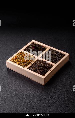 Une boîte en bois avec plusieurs types de thé séché, vert, noir, fruit, et camomille. Thé sec dans la boîte Banque D'Images