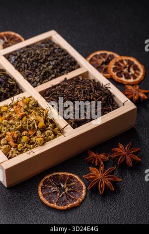 Une boîte en bois avec plusieurs types de thé séché, vert, noir, fruit, et camomille. Thé sec dans la boîte Banque D'Images