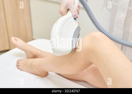 Gros plan d'épilation au laser de jambe féminine en clinique de beauté avec dermatologue Banque D'Images