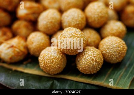 Gros plan de boules de sésame dorées frites disposées sur une feuille de banane, dessert traditionnel asiatique sucré. Banque D'Images