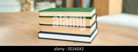 Pile de quatre livres à couverture rigide sur une table en bois dans une pièce lumineuse Banque D'Images