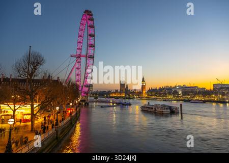 Alors que le crépuscule descend au-dessus de Londres, le London Eye brille dans des tons de rose, se reflétant sur la Tamise. Banque D'Images