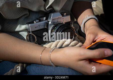 Vintage Minolta SR-T 101 caméra reposant sur une corde à côté d'une personne tenant un téléphone. Banque D'Images