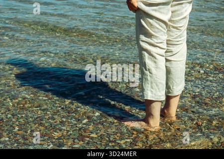 Personne en pantalon beige se tient dans l'eau, ombre projetée sur le fond marin galbé. Waterton, Alb Banque D'Images