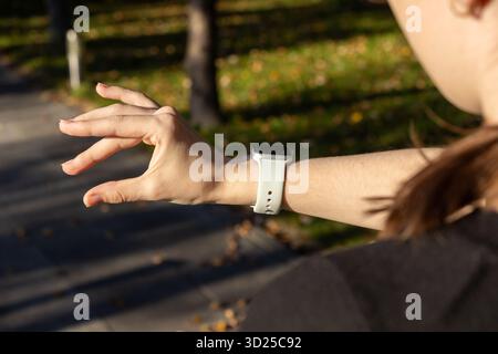 Poznan, Pologne - 24 septembre 2025 : la main de la personne interagit avec l'Apple Watch blanche en extérieur, symbolisant la connectivité numérique, la santé et l'acte moderne Banque D'Images