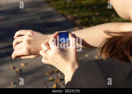 Poznan, Pologne - 24 septembre 2025 : gros plan de la main d'une femme interagissant avec son Apple Watch, affichant des informations météo en temps réel, indiquant Banque D'Images