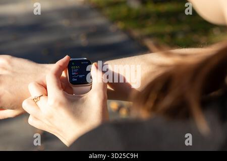 Poznan, Pologne - 24 septembre 2025 : la main d'une personne interagit avec une Apple Watch, montrant la progression de l'exercice en temps réel pour le moniteur de santé personnel Banque D'Images