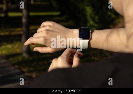 Poznan, Pologne - 24 septembre 2025 : poignet d'une personne portant une Apple Watch, affichant des données de forme physique, y compris la fréquence cardiaque et les calories, pour une santé active Banque D'Images