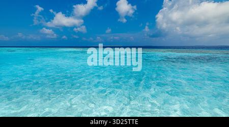 Océan turquoise calme, récif corallien dans une eau peu profonde, ciel bleu panorama. Paysage marin tropical. Fond de papier peint pour voyages en vacances d'été, paradis Banque D'Images