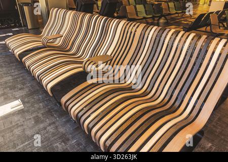 Banc en bois moderne avec design rayé incurvé dans la zone d'attente de l'aéroport sur fond. Miami. ÉTATS-UNIS. Banque D'Images