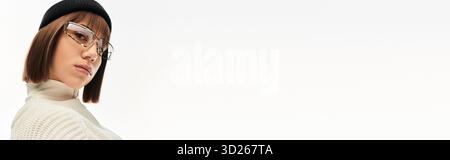 Une jeune femme respire la confiance dans une tenue chic tout en se tenant sur une toile de fond minimaliste. Banque D'Images