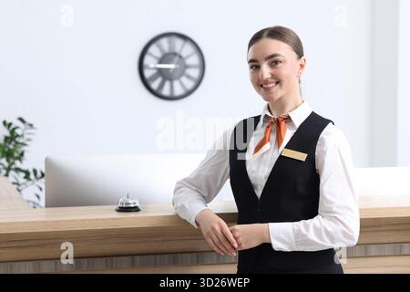 Heureux réceptionniste en uniforme près de la réception à l'intérieur Banque D'Images