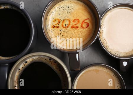Bonjour Nouvelle année 2026. Tasse de café avec des numéros entre autres sur la table grise, vue de dessus Banque D'Images