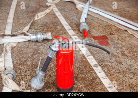 Cylindre d'extincteur rouge avec tuyaux d'incendie déroulés. Banque D'Images