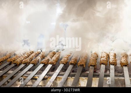 Le kebab traditionnel turc adana cuisine au grill. Kebab de style turc. Cuisson des kebabs Adana sur le grill de style restaurant, fumée sortant de th Banque D'Images