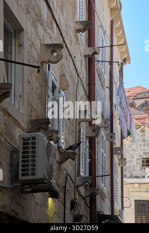Façade de bâtiment en pierre à Dubrovnik, Croatie, montrant un contraste entre l'ancien et le nouveau : supports en pierre sculptée historiques et une unité de climatisation moderne. Banque D'Images