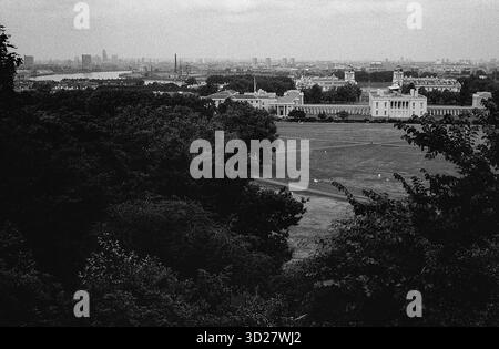 Vue panoramique depuis l'Observatoire royal de Greenwich, révélant une vaste étendue de l'horizon londonien. Le bâtiment historique se dresse bien en vue au milieu de la vaste étendue de Greenwich Park, offrant un aperçu lointain de la Tamise et des monuments emblématiques de la ville. Une scène britannique classique de science, d'histoire et de beauté urbaine. Banque D'Images