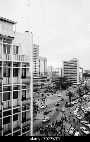 Le quartier central des affaires de Nairobi présente un mélange d'architecture moderne et de vie urbaine animée. Cette scène de rue emblématique capture le cœur de la capitale du Kenya, avec des bâtiments imposants bordant la rue et une foule dynamique naviguant sur la rue. L’image offre un aperçu de l’énergie dynamique de la ville, témoignage de sa croissance et de son importance en Afrique de l’est. Banque D'Images