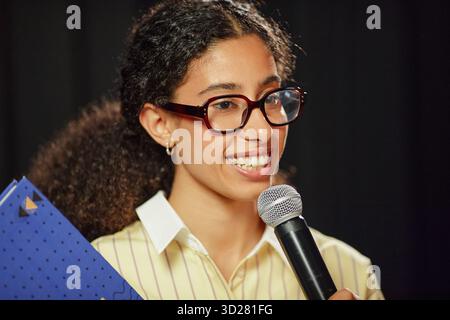 Portrait de jeune femme adulte parlant dans le microphone sur scène Banque D'Images