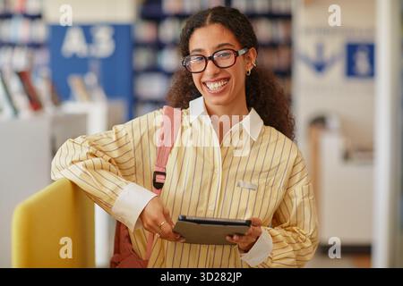 Portrait de jeune adulte BiracialWoman souriant tout en utilisant la tablette numérique Banque D'Images
