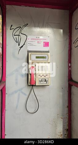 Téléphone payant rétro T-Mobile / téléphone public dans une cabine téléphonique couverte de graffitis et altérée à Budapest Banque D'Images