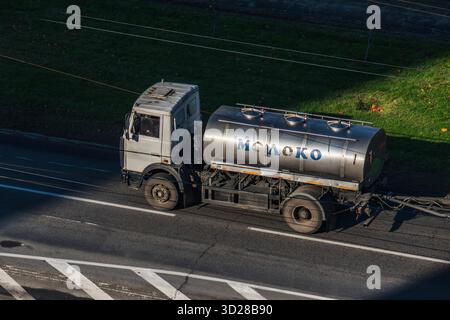 Camion-citerne cylindrique en acier inoxydable avec le mot « lait » écrit en cyrillique, conduisant dans une rue de la ville. Thème transport et logistique au quotidien Banque D'Images