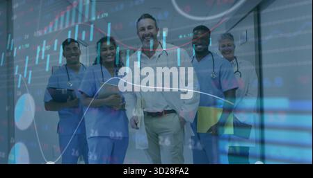 Équipe médicale en marche portant des manteaux blancs et des gommages dans le couloir de l'hôpital avec des stéthoscopes, des cartes Banque D'Images