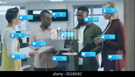 Quatre professionnels de l'habillement professionnel examinant les métriques des médias sociaux au bureau, avec des documents sur les ordinateurs portables Banque D'Images