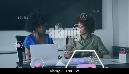 Collaborateurs portant des vêtements professionnels analysant les données dans une salle de réunion, avec ordinateur portable, écran Banque D'Images