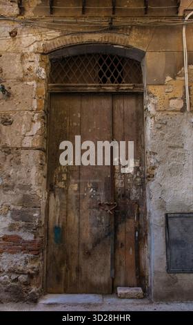 Une porte rustique en bois à Palerme, Sicile, Italie. La double porte est fortement altérée, avec les restes de vieilles photos attachées à elle Banque D'Images