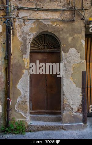 Une porte en métal rouillé à Palerme, Sicile, Italie. La double porte est fortement altérée, elle dispose d'un tableau arrière orné en fer forgé Banque D'Images
