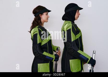 Deux athlètes féminines dans le matériel de tir isolé sur fond blanc, photo de produit présentant des vêtements de sport et fusil, studio shot avec un minimum propre Banque D'Images