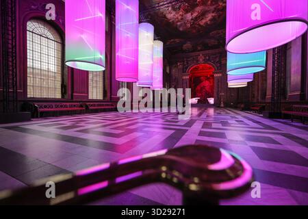 Londres, Royaume-Uni. 31 octobre 2025. Personnel avec les installations de Peter Walker 'Connection' and Identity' dans le Painted Hall de l'Old Royal Naval College, Greenwich. « Identity » montre huit colonnes suspendues illuminées, évoquant les structures de l'ADN, et « Connection » est une réinterprétation moderne de la création d'Adam de Michel-Ange, remplaçant les mains traditionnellement masculines par des moulages de mains féminines. Crédit : Imageplotter/Alamy Live News Banque D'Images