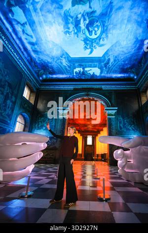 Londres, Royaume-Uni. 31 octobre 2025. Personnel avec les installations de Peter Walker 'Connection' and Identity' dans le Painted Hall de l'Old Royal Naval College, Greenwich. « Identity » montre huit colonnes suspendues illuminées, évoquant les structures de l'ADN, et « Connection » est une réinterprétation moderne de la création d'Adam de Michel-Ange, remplaçant les mains traditionnellement masculines par des moulages de mains féminines. Crédit : Imageplotter/Alamy Live News Banque D'Images