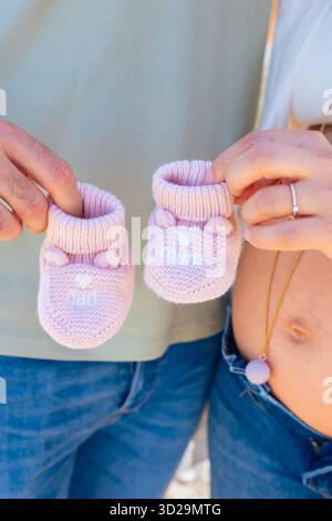 Gros plan d'un couple tenant des chaussons roses sur les mains attendant une fille Banque D'Images