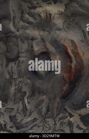 Vue aérienne de textures volcaniques peignent un paysage sombre avec des gris discrets et des rouges ardents, Highlands d'Islande, Sveitarfélagið Hornafjörður, Islande. Banque D'Images