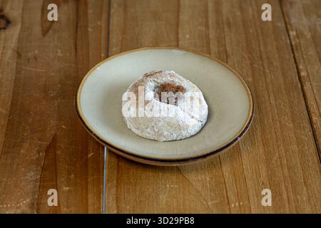 Buccellato, un biscuit traditionnel sicilien rempli de figue, saupoudré de sucre en poudre, assis sur une assiette sur une surface en bois Banque D'Images