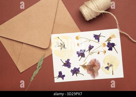 Fleurs pressées et séchées avec de la ficelle sur fond brun. Banque D'Images