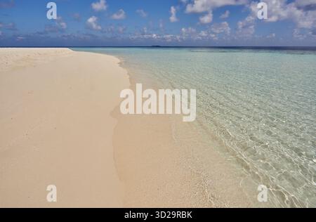 Une plage tropicale de sable blanc baignée par les eaux aigue-marine calmes d'un lagon, abritée par un récif de corail ; dans les Maldives, océan Indien. Banque D'Images