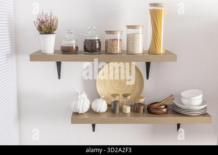 Ouvrez les étagères en bois avec divers bocaux en verre avec un couvercle en bois rempli d'épices, de café, de spaghettis. décoration élégante dans la cuisine moderne. vue de face Banque D'Images